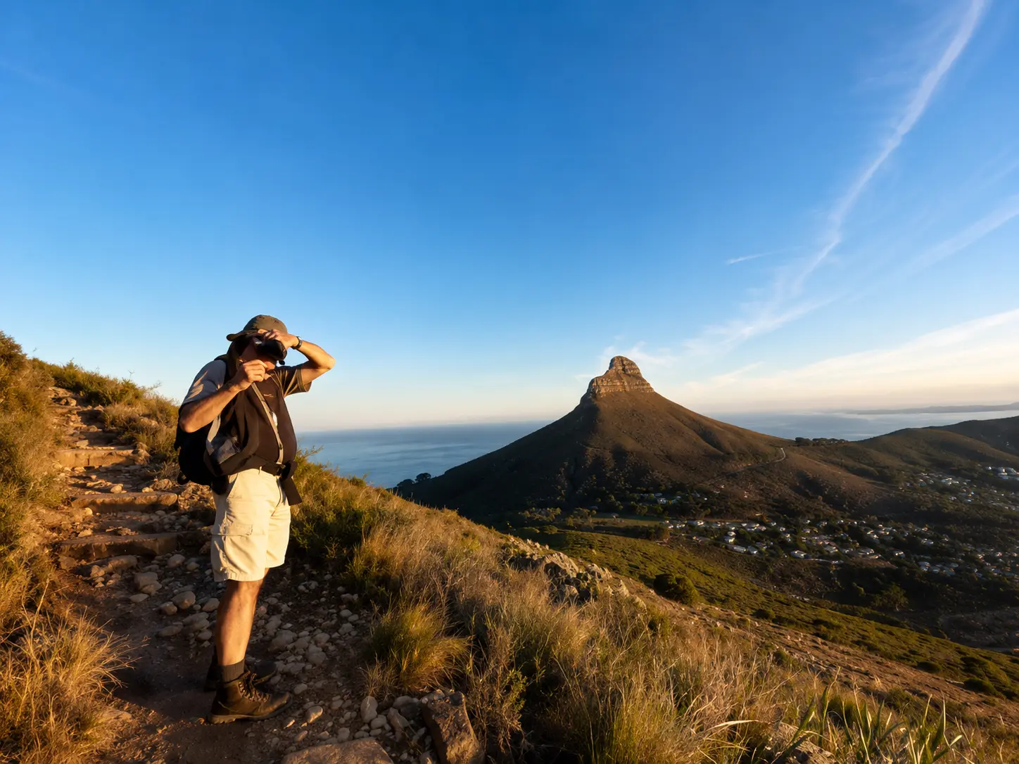 Hiker on a Table Mountain trail overlooking Lion’s Head and the Atlantic Ocean in Cape Town.
