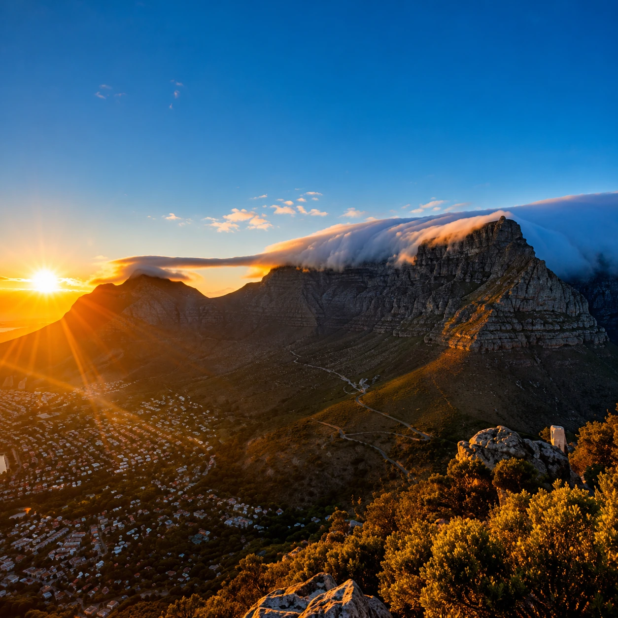 Sunrise over Table Mountain with the iconic tablecloth cloud cascading over the cliffs in Cape Town, South Africa.